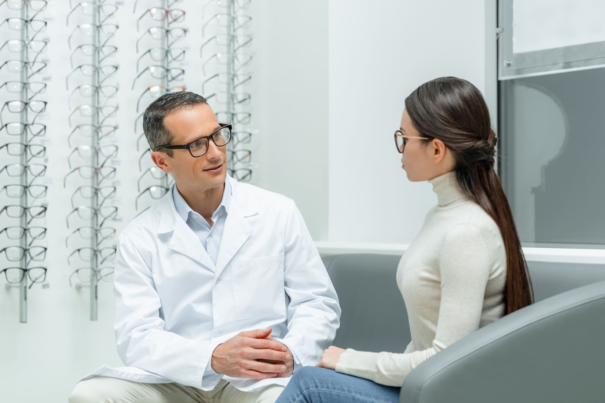 side view of ophthalmologist and young woman having conversation in optics side view of ophthalmologist and young woman having conversation in optics