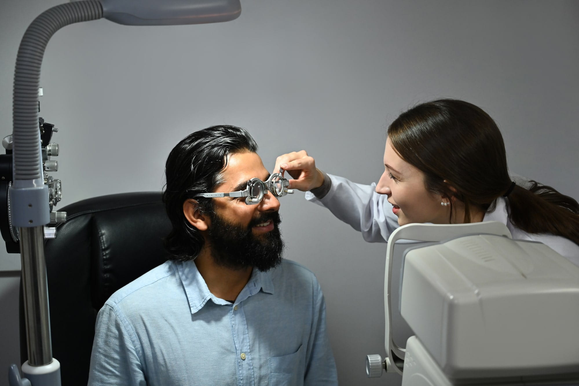 Smiling Indian male checking eye vision with ophthalmologist in