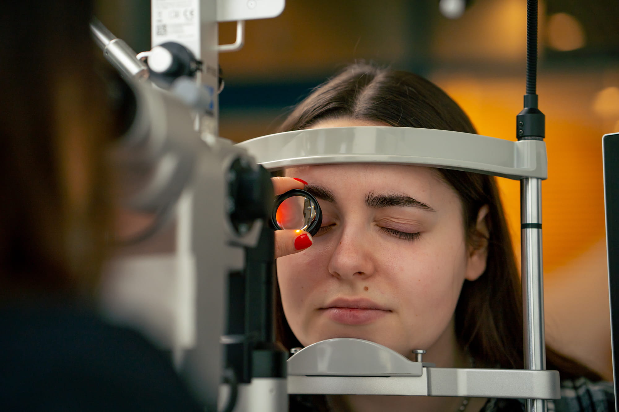 close up in an ophthalmology clinic young doctor diagnoses a young girl with a magnifying lens